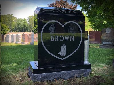 Black Granite Upright Monument Brown Memorial with Heart Shaped Panel and Book Sculpted on Top with Portrait Etchings and Praying Hands Carving